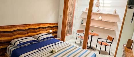 Quarto de hotel com cama, uma mesinha e uma cadeira.