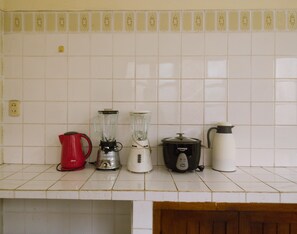 A kitchen countertop with a red kettle, a white blender, a black slow cooker, and a white electric kettle. - La Casa del Paucar (Iquitos)