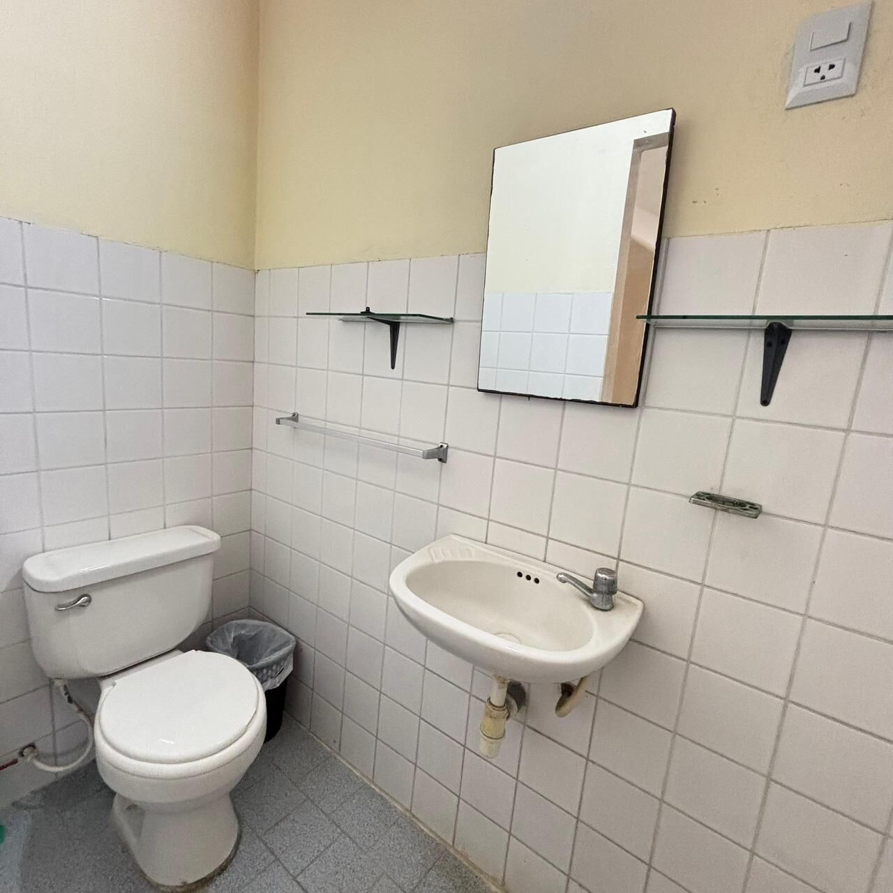 A small bathroom with a toilet, sink, and mirror.