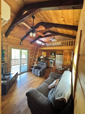A cozy cabin interior with a living room, kitchen, and a balcony. - Sunshine Cabin is ready to provide you with a peaceful stay! (Hot Springs)