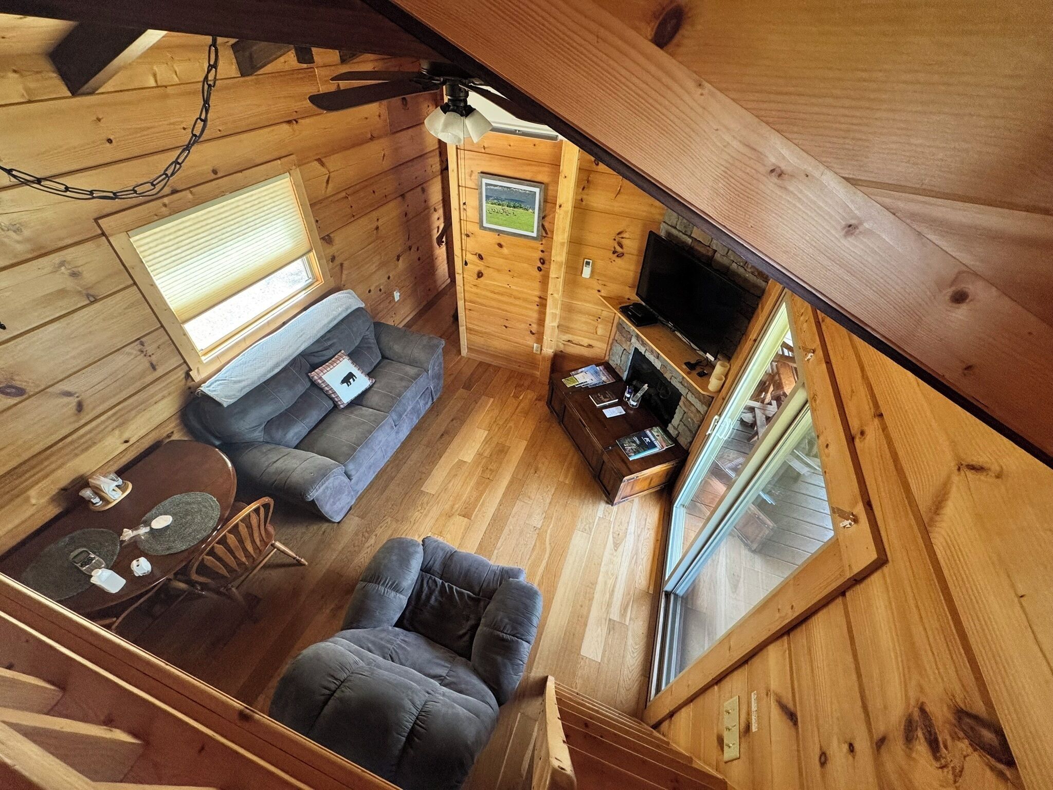 A cabin interior with a sofa, armchair, dining table, and a television.
