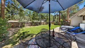 A patio with a table and chairs, a hot tub, and a wooden deck. - Bear-Ski Cabin: Hot Tub, Pets, BBQ (South Lake Tahoe)