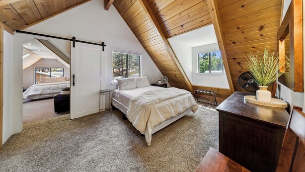 A bedroom with a sloped ceiling, a bed, a dresser, and a window. - Bear-Ski Cabin: Hot Tub, Pets, BBQ (South Lake Tahoe)