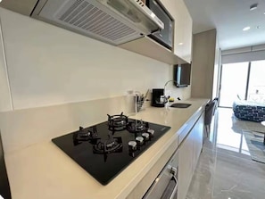 A modern kitchen with a black stove, white cabinets, and a large window. - Luxury Apartment at Bello Horizonte Beach, Santa Marta (Santa Marta)