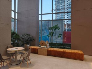 A modern interior with a round table and chairs, a wooden bench, and a view of a building through large windows. - Luxury Apartment at Bello Horizonte Beach, Santa Marta (Santa Marta)