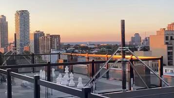 A rooftop terrace with a cityscape view during sunset.