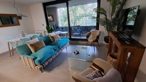 A modern living room with a sofa, armchairs, a coffee table, and a television. - Cozy 2-bedroom apartment in serene Pucon with AC (Pucon)