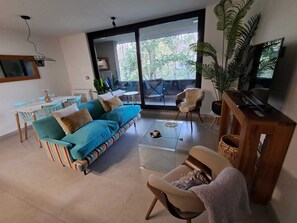 A modern living room with a sofa, armchairs, a coffee table, and a television. - Cozy 2-bedroom apartment in serene Pucon with AC (Pucon)