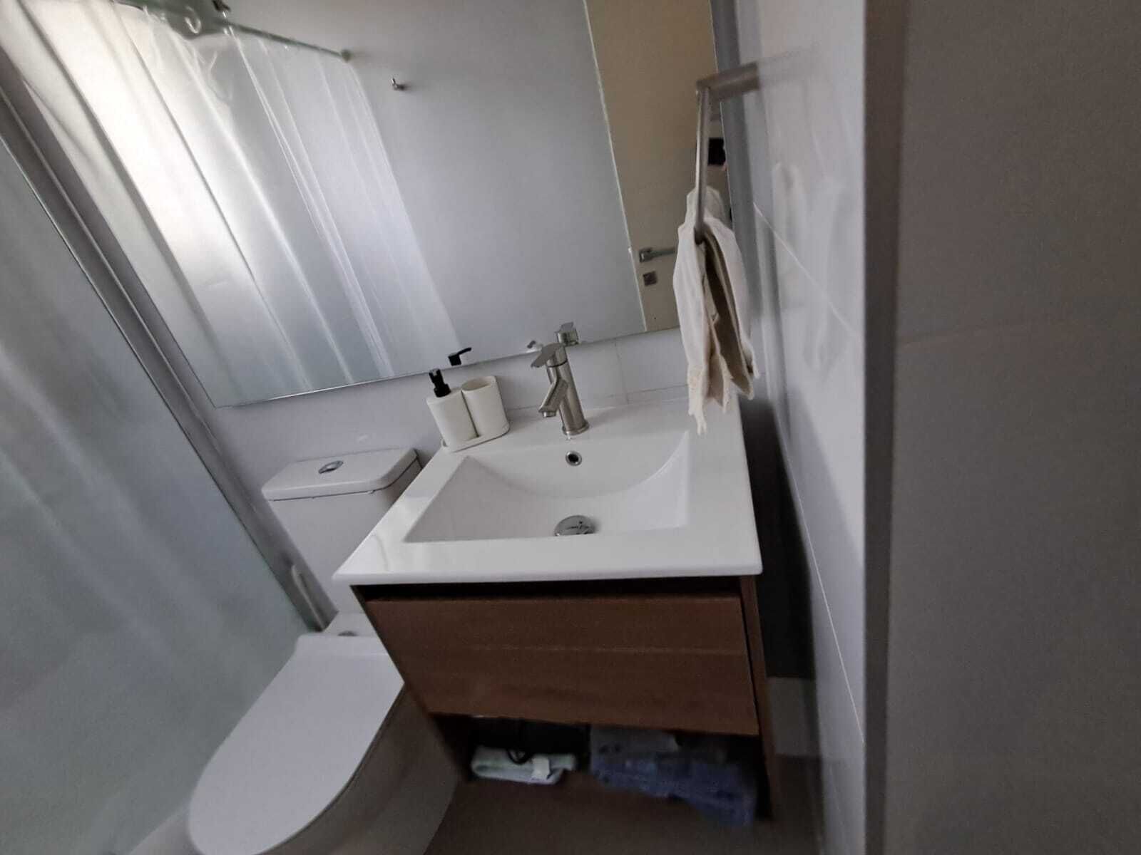 A modern bathroom with a white sink, a mirror, a towel rack, and a toilet.
