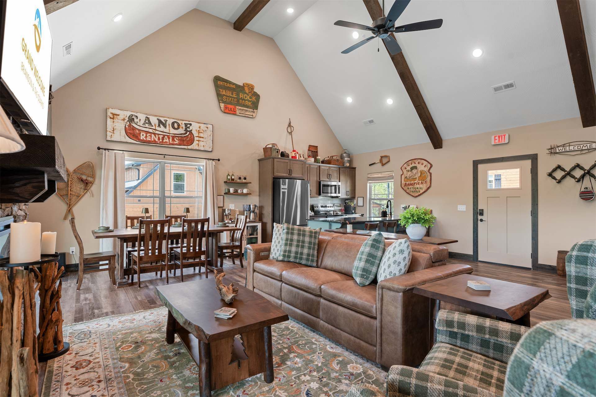 A spacious living area with a high ceiling, a dining table, a sofa, and a kitchen in the background.