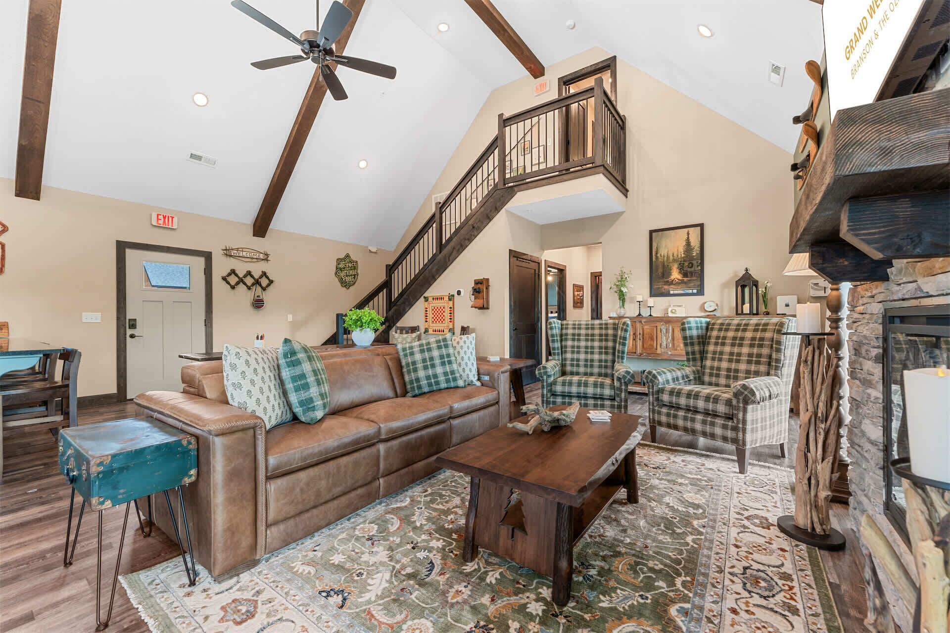 A spacious living room with a high ceiling, a wooden staircase, and a fireplace.