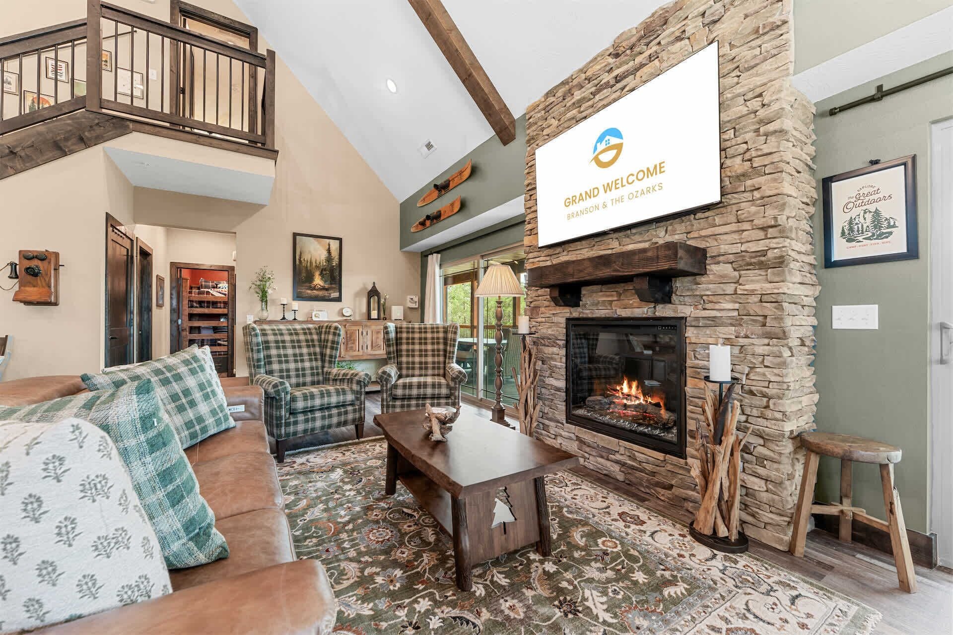 A spacious living room with a stone fireplace, a high ceiling, and a view of the outdoors.