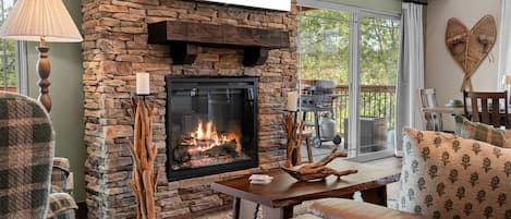A cozy living room with a stone fireplace, a comfortable sofa, and a dining area with a table.