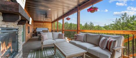 A covered outdoor seating area with a fireplace, a sofa, and a table.