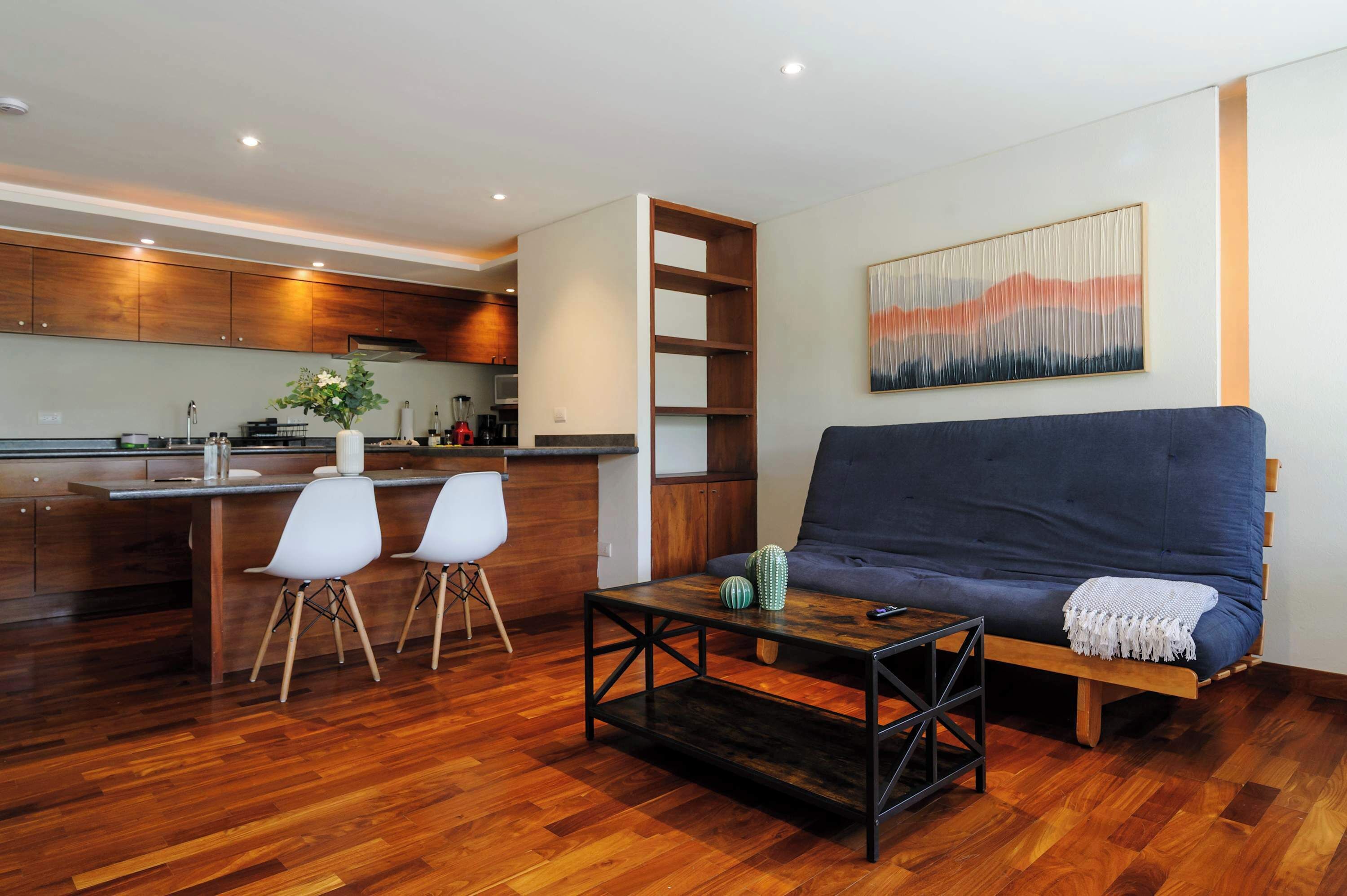 Un salon moderne comprenant un canapé, une table basse et un coin cuisine avec des meubles en bois et une table à manger.