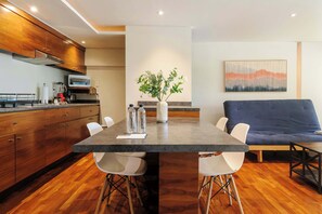 A modern kitchen with wooden cabinets, a built-in microwave, and a dining area with a table and chairs. - w* | Amazing 1BR in Polanco (Ciudad de México)