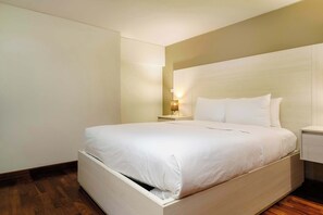 A neatly made bed in a hotel room with a wooden headboard, a bedside table with a lamp, and a wooden floor. - w* | Amazing 1BR in Prime Polanco (Ciudad de México)