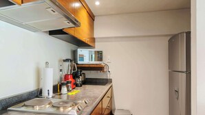 Une cuisine de taille réduite équipée d’un four à micro-ondes, d’une cuisinière et d’une poubelle.
