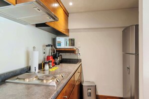 A compact kitchen with a microwave, stove, and a trash bin. - w* | Amazing 1BR in Prime Polanco (Ciudad de México)
