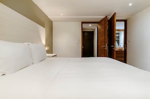 A bedroom with a large bed, a nightstand, a bedside lamp, and a wooden wardrobe. - w* | Amazing 1BR in Polanco (Ciudad de México)