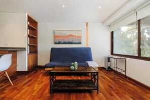 A living room with a blue sofa, a wooden coffee table, and a radiator. - w* | Amazing 1BR in Prime Polanco (Ciudad de México)