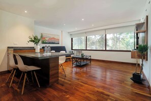 A modern kitchen with a bar area, wooden flooring, and a large window offering a view of the outdoors. - w* | Amazing 1BR in Polanco (Ciudad de México)