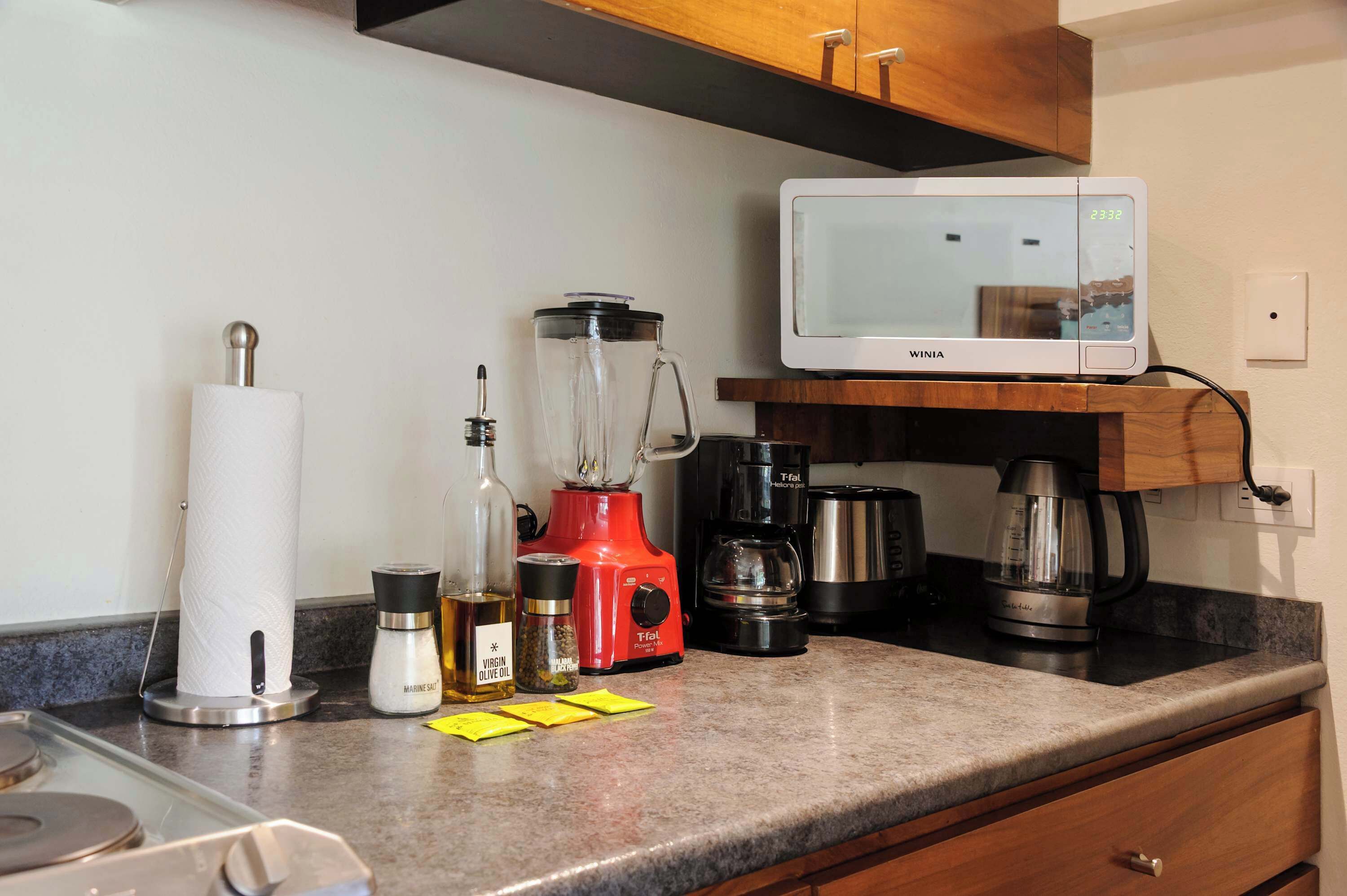 A kitchen counter with a blender, a microwave, and various kitchen items.