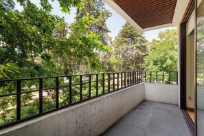 A balcony with a concrete floor, a metal railing, and a view of a green landscape with trees. - w* | Deluxe 1BR  Duplex in Prime Polanco (Ciudad de México)