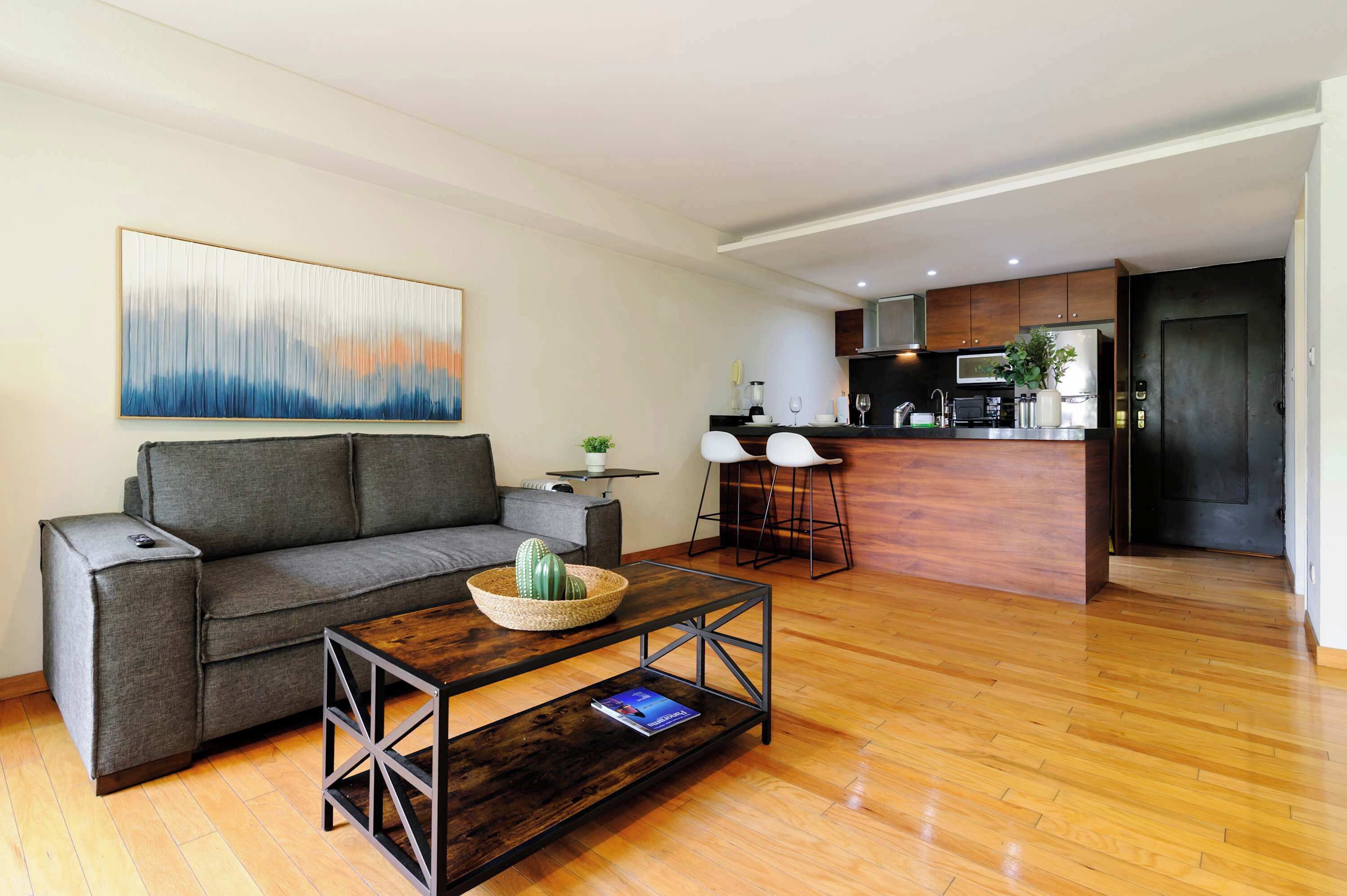 Een moderne woonkamer met een bank, salontafel en een keukenhoek met een barstoel.