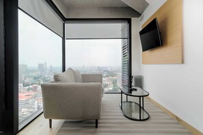 Ein modernes Wohnzimmer mit einer Couch, einem Glastisch und einem an der Wand befestigten Fernseher.