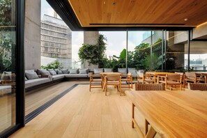 Ein modernes Interieur mit Holzbalkendecke, großen Fenstern, einer Couch und einem Essbereich.