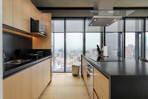 A modern kitchen with a city view, featuring a stainless steel sink, black countertop, and wooden cabinets. - w* | Stylish 1BR in Juarez (Ciudad de México)