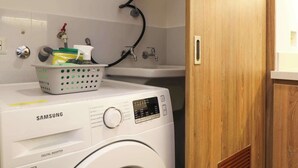 Een wasserette met een Samsung wasmachine, een boiler en een mand op de wasbak.