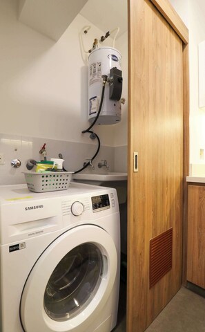 A laundry room with a Samsung washing machine, a water heater, and a basket on the sink. - w* | Charming 2BR w/ Balcony & View in Miraflores (Miraflores)