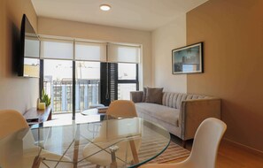 A modern living room with a glass table, a sofa, and a TV mounted on the wall. - w* | Bright 2BR w/ Balcony & View in Miraflores (Miraflores)