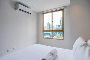 Ein Hotelzimmer mit Bett, Fenster mit Stadtblick, Klimaanlage und Steckdosen.