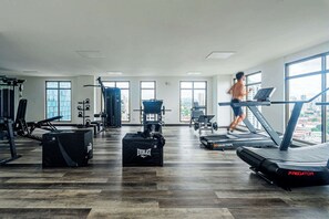 Ein Fitnessstudio mit Laufbändern, Krafttrainingsgeräten und Kurzhanteln.