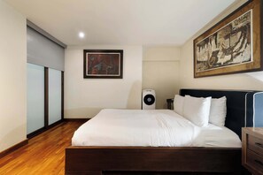 Ein Hotelzimmer mit einem Bett, einem großen Gemälde an der Wand, einer Deckenleuchte und einem Lautsprecher.