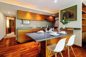 A modern kitchen with wooden cabinets, a marble countertop, and a dining area with white chairs. - w* | Luxury 1BR in Polanco (Ciudad de México)