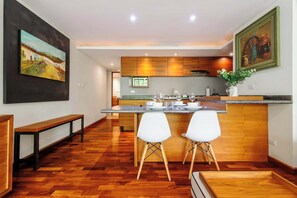 A modern kitchen with wooden cabinets, a central island with seating, and a painting above the island.