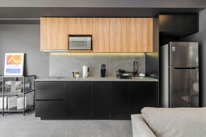 Eine moderne Küche mit schwarzen Schränken, einem Edelstahl-Kühlschrank und einer Mikrowelle über der Arbeitsfläche.