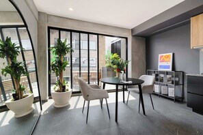 A modern interior with a dining area, potted plants, and a view through large windows. - w* | Sunlit Loft in Tabacalera w/ Private Terrace (Ciudad de México)