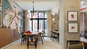A modern dining area with tables and chairs, a mural on the wall, and large windows. - w* | Sunlit Loft w/ Private Terrace in Tabacalera (Ciudad de México)