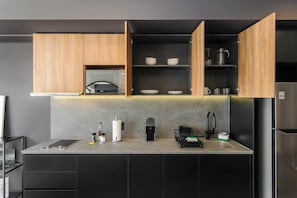 Eine moderne Küche mit Holzschränken, einer eingebauten Mikrowelle und einem Edelstahlkühlschrank.