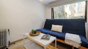 A small living room with a blue sofa, a white coffee table, and a radiator. - w* | Charming & Cozy 1BR in Prime Polanco (Ciudad de México)
