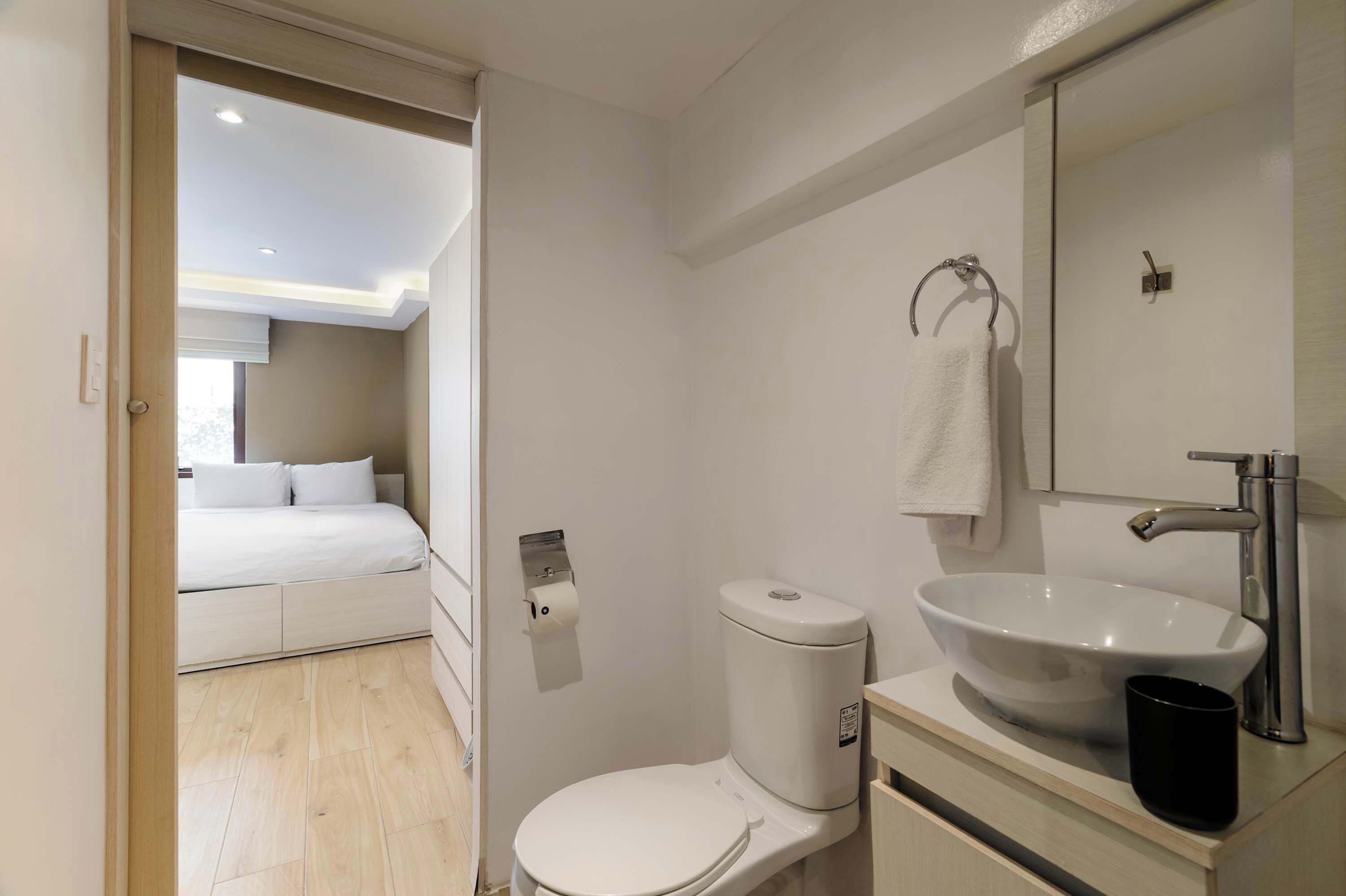 A modern bathroom with a toilet, sink, and mirror.
