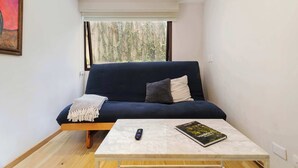 A modern living room with a dark blue sofa, a white coffee table, and a book. - w* | Enchanting 1BR in Prime Polanco (Ciudad de México)