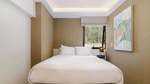 A neatly made bed in a room with a skylight, a nightstand, and a painting on the wall. - w* | Enchanting 1BR in Prime Polanco (Ciudad de México)