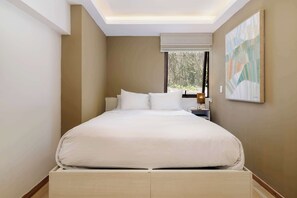A neatly made bed in a room with a skylight, a nightstand, and a painting on the wall. - w* | Enchanting 1BR in Prime Polanco (Ciudad de México)