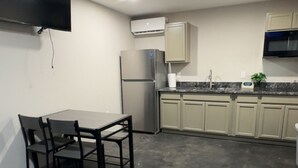 A compact kitchen with a dining table and chairs, a built-in oven, and a flat-screen TV mounted on the wall. - Cozy 1-bedroom apartment in marvelous Odessa with AC (Odessa)